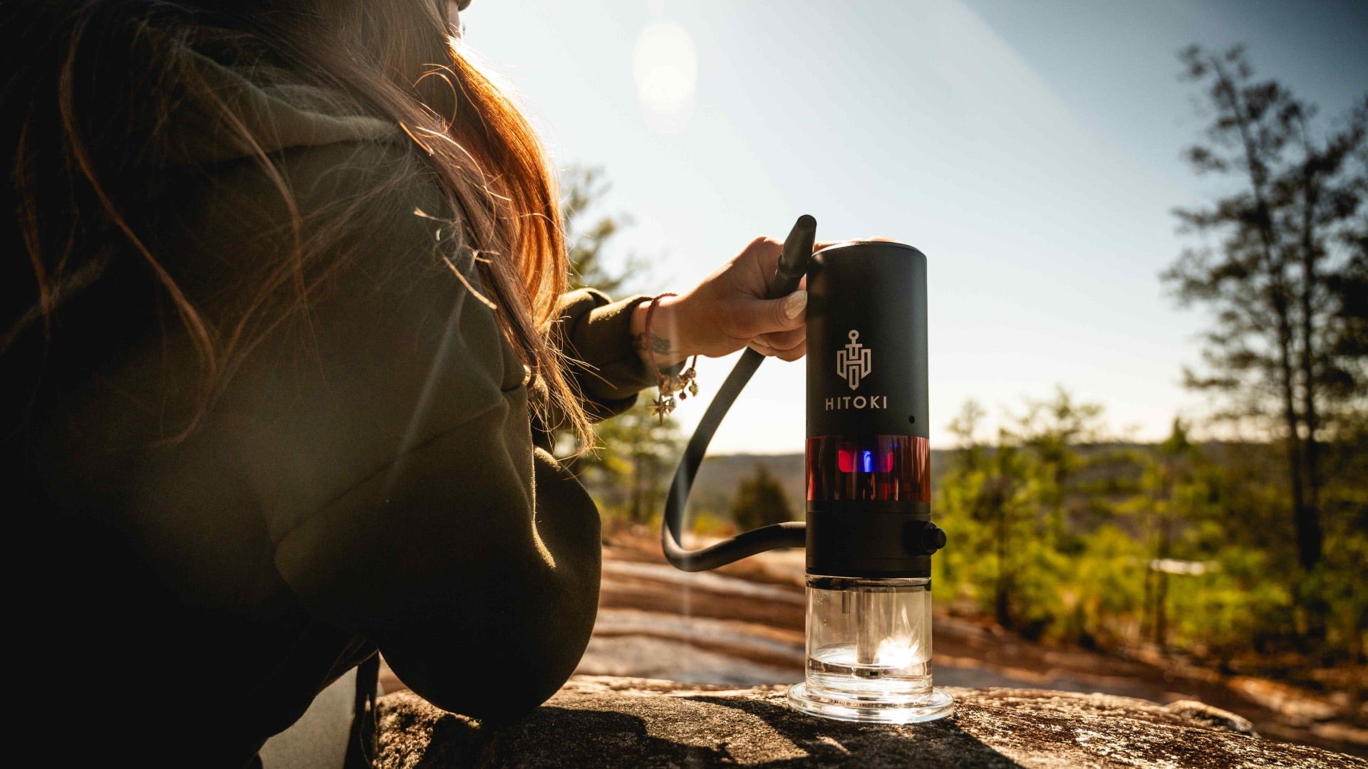 Hitoki Trident V3 on a rock ledge outdoors, highlighting its long-lasting battery life with over 280 uses per charge.