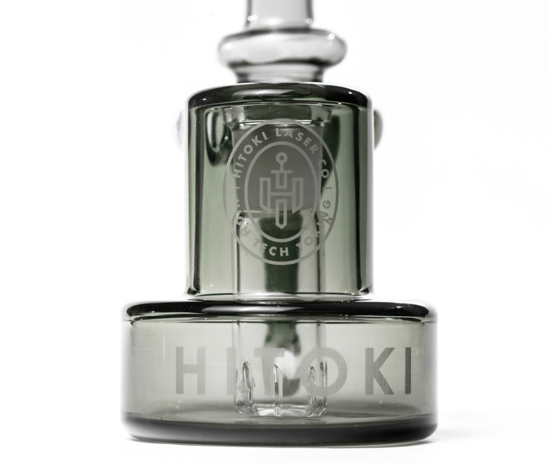 Close-up of Hitoki Saber Recycler Attachment showcasing etched logo and precision-crafted glass base design.